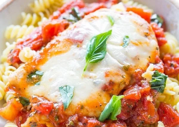 Plate of flavorful Tomato Basil Chicken garnished with fresh basil leaves.